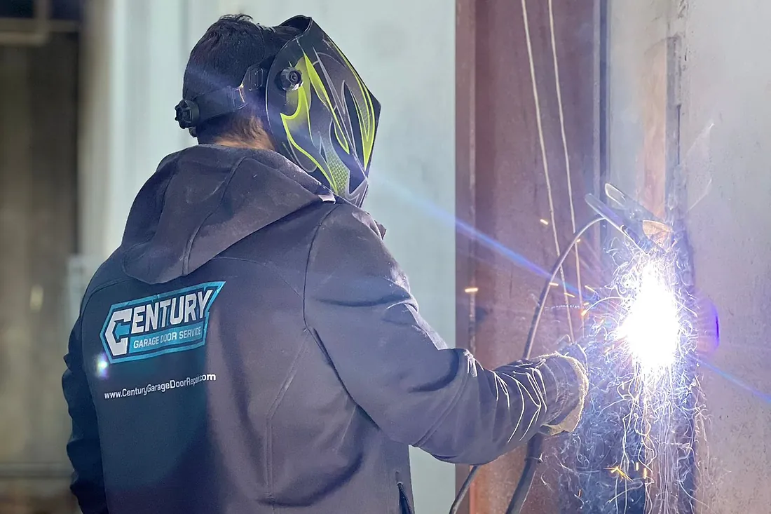 Century technician welding and repairing a garage door panel